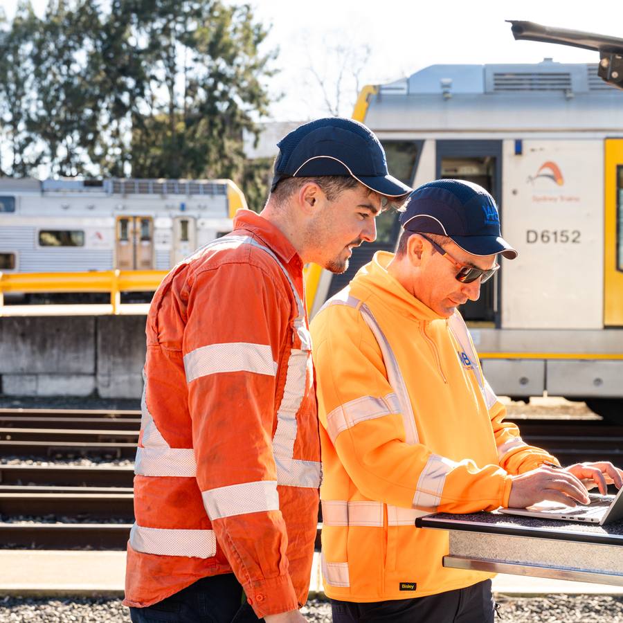Two WB crew reviewing a job on a laptop at a rail yard.