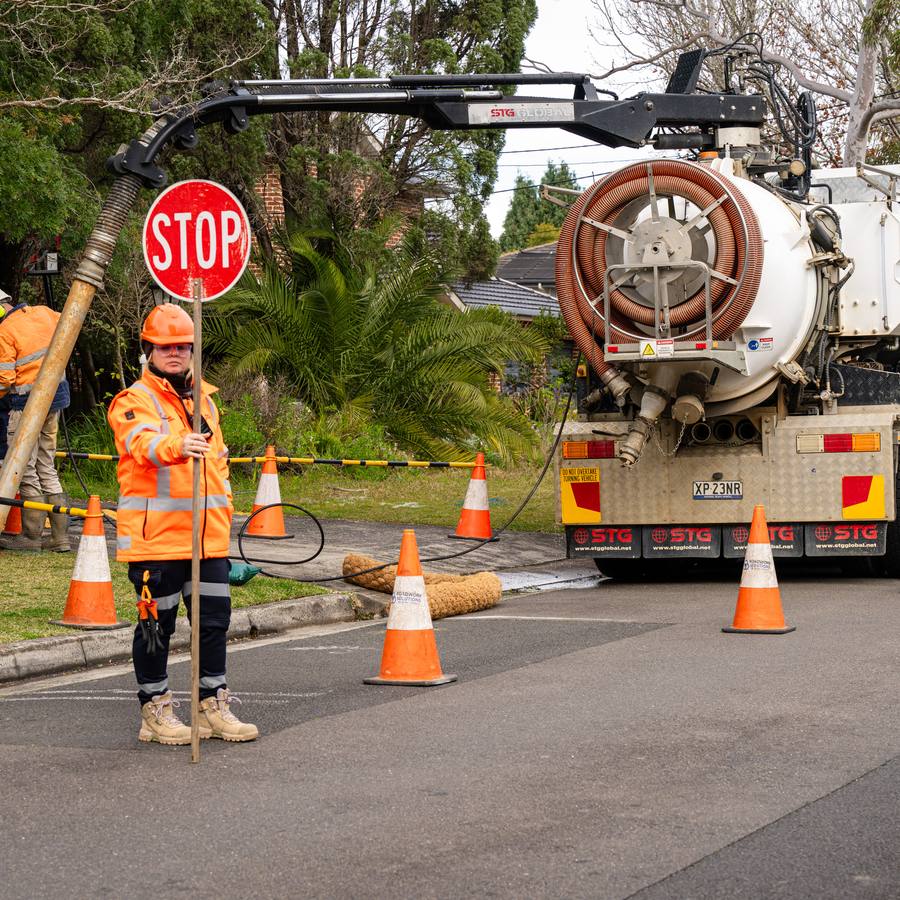 A WB vacuum truck at work behind traffic control.