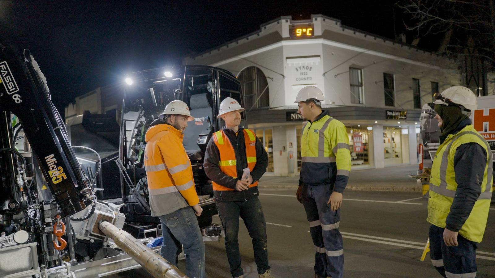 A WB Infrastructure crew on a closed street at night under floodlights.