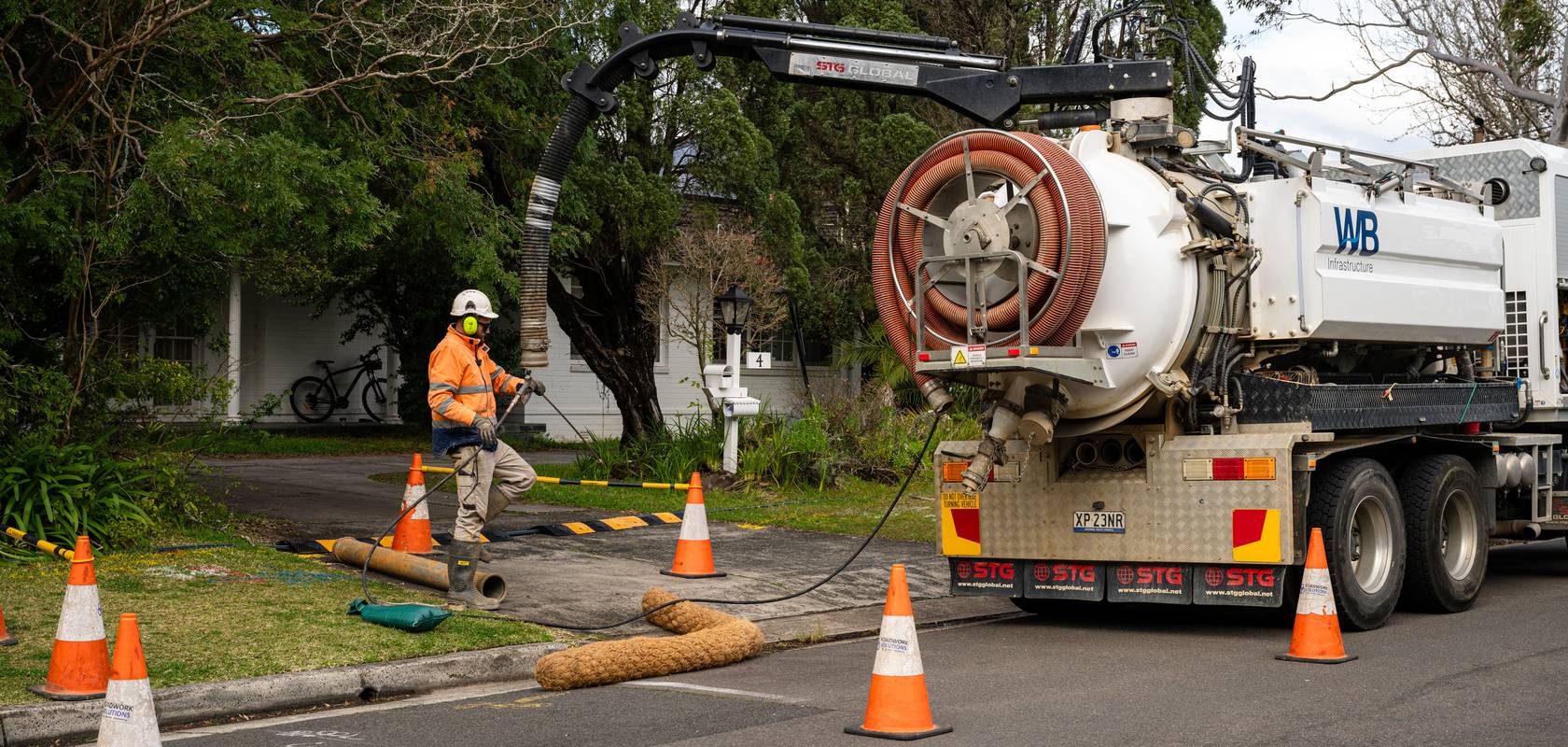 A WB vacuum truck and crew on a suburban street.